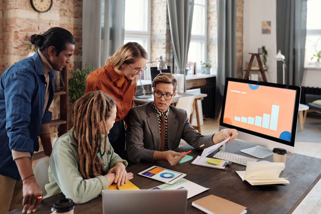 A group of diverse professionals discussing digital marketing plans in a modern office setting.